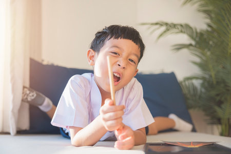 Happy Asian boy 6-7 years old, black hair, white skin, wearing white shirt and blue shorts looking at camera. Children in school uniforms of Thailand. concept about education, play, creativity.の写真素材