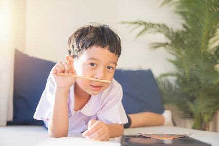 Happy Asian boy 6-7 years old, black hair, white skin, wearing white shirt and blue shorts looking at camera. Children in school uniforms of Thailand. concept about education, play, creativity.の写真素材