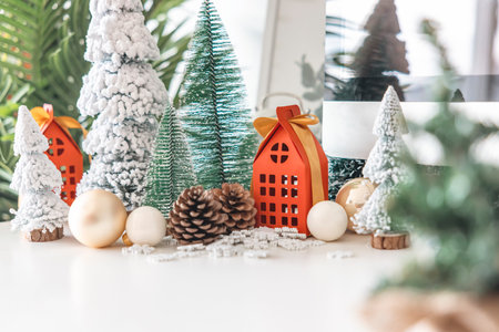 Festive scene is a beautiful Christmas tree adorned, with Christmas balls, pine cones, and a red house gift box tied with golden ribbon. Christmas mockup with space for text.の写真素材