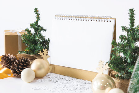 The White calendar mock up to enter text by the festive scene of beautiful Christmas tree adorned, with Christmas balls, pine cones, red house gift box tied golden ribbon. concept about Important day.の写真素材