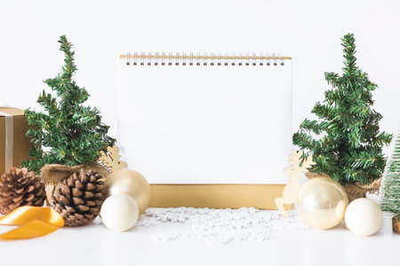The White calendar mock up to enter text by the festive scene of beautiful Christmas tree adorned, with Christmas balls, pine cones, red house gift box tied golden ribbon. concept about Important day.の写真素材