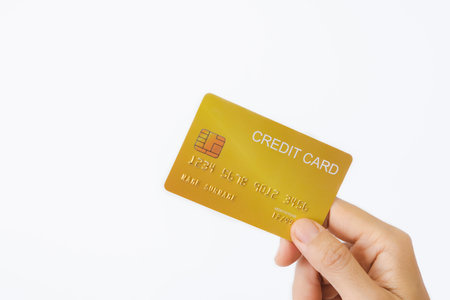 Woman's right hand holds a golden credit card, isolated on a white background. Concept of technology, connection, communication, social, online shopping.の写真素材