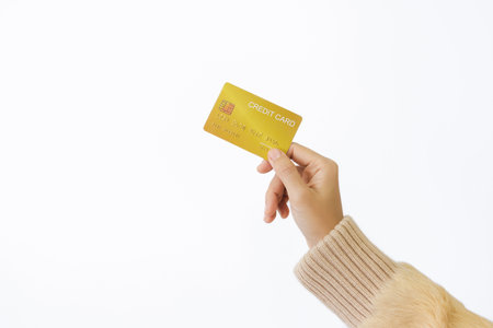 Woman's right hand holds a golden credit card, isolated on a white background. Concept of technology, connection, communication, social, online shopping.の写真素材