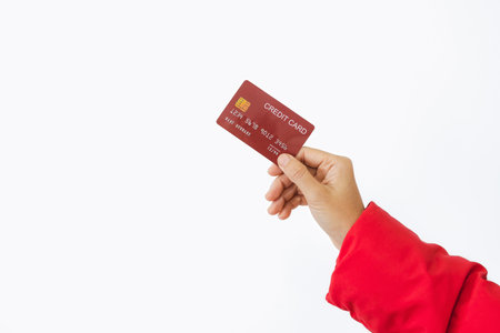 Woman's right hand holds a red credit card, isolated on a white background. Concept of technology, connection, communication, social, online shopping.の写真素材