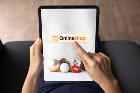 Close-up woman's hand holds tapelet uses his finger to press buttons on screen mobile. online shopping offers, Christmas background. Concept of Marketing, Shopping, technology, connection.の写真素材