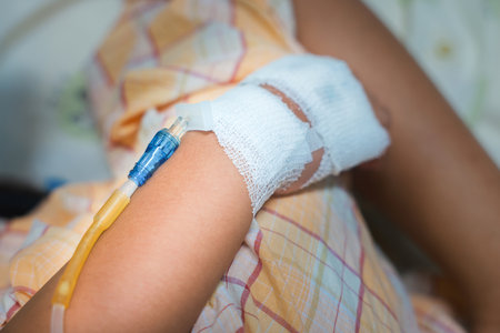 Close up child hand with tube of normal saline infusion at the hospital because it is influenza A. Hand of a patient in Hospital ward. Concept about treatment, emergency, medical, chemotherapy, sick.の写真素材