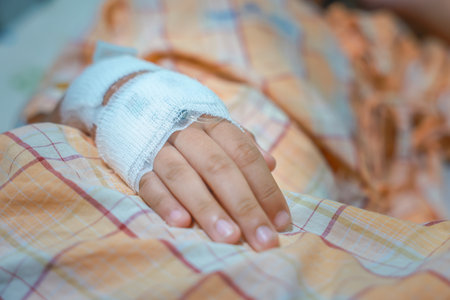 Close up child hand with tube of normal saline infusion at the hospital because it is influenza A. Hand of a patient in Hospital ward. Concept about treatment, emergency, medical, chemotherapy, sick.の写真素材