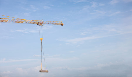 Tower cranes at construction site on sky background. Multi Storey Residential Buildings construction. Tower crane on Housing renovation. tower crane is attached to boom load secured with steel cables.の写真素材