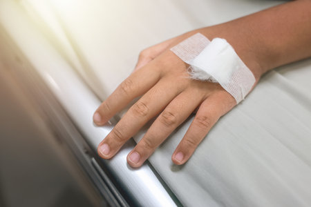 Close up child hand with tube of normal saline infusion at the hospital because it is influenza A. Hand of a patient in Hospital ward. Concept about treatment, emergency, medical, chemotherapy, sick.の写真素材