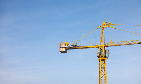 Tower cranes at construction site on sky background. Multi Storey Residential Buildings construction. Tower crane on Housing renovation. tower crane is attached to boom load secured with steel cables.の写真素材