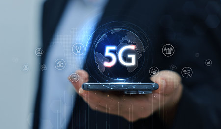 Hand holding smartphone with 5G icon and global network interface, representing high-speed wireless...