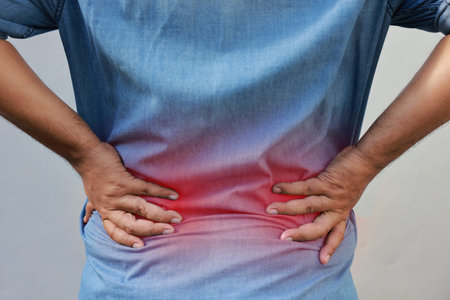 Middle aged Asian man suffering from chronic back pain or office syndrome while sitting. Red...