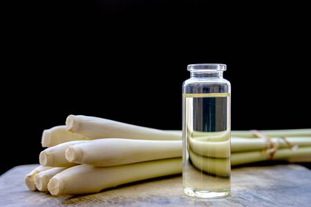 Lemongrass Essential oil bottle with fresh Lemongrass, placed on a wooden plate and have a black background.の写真素材