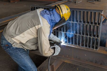 The welder is welding a steel structure work with process Flux Cored Arc Welding(FCAW) and dressed...