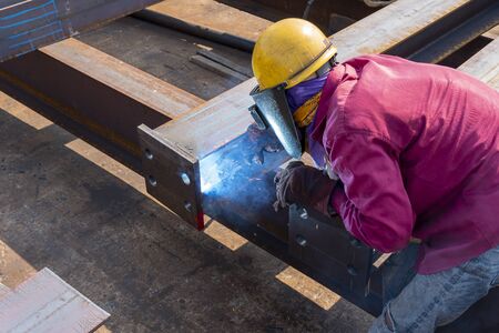 The welder is welding a steel structure work with process Flux Cored Arc Welding(FCAW) and dressed...