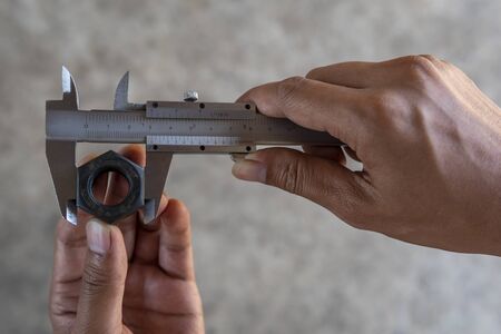 Using Vernier caliper to measure the dimensions of the nut.の写真素材