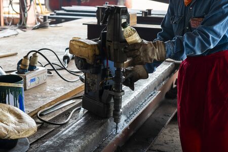 Close up worker are using a drilling machine to drill a hole equal angles in industrial factory.の写真素材