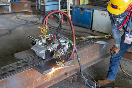 Workers are using gas cutting machines to cutting steel plates for steel structure fabrication,...