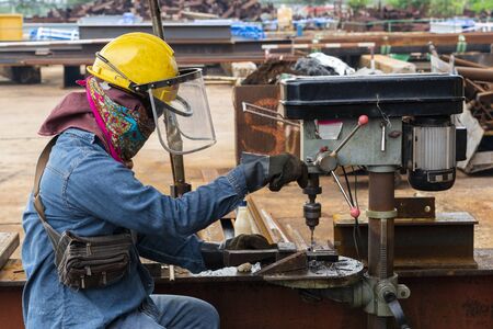 Close up Men are using a drill press to drill a hole steel rod in industrial factory.