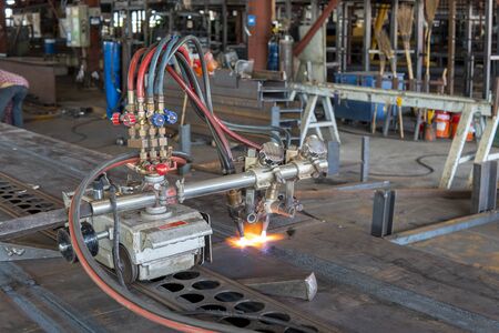 Using gas cutting machines to burning bending steel plates that is curled after welding for built-up h-beam at industrial factory.の写真素材