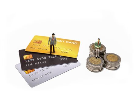 Miniature figure businessman standing on credit card and sitting on stacked coin, isolated on white backgroundの写真素材