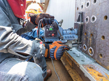 Worker are using a drilling machine to drill a hole on steel plate at industrial factory.