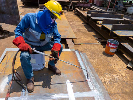 Workers are using heating torch to burning bending steel plates that is curled after welding.の写真素材