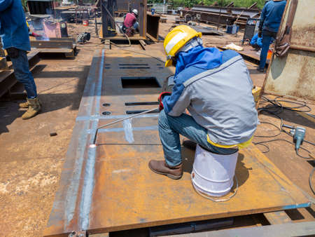 Workers are using heating torch to burning bending steel plates that is curled after welding.の写真素材