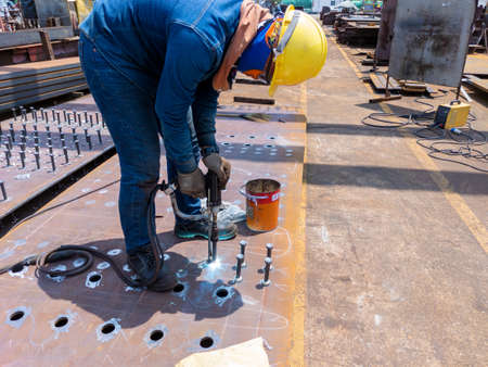 Welder is using a Stud Welding Machine to weld stud bolt on steel plate, at industrial factory.の写真素材