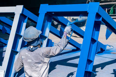 The painter uses a spray gun to paint a steel structure before transportation to the assembly yard.の写真素材