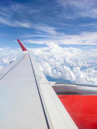 Airplane wings on blue sky and fluffy white clouds.の写真素材