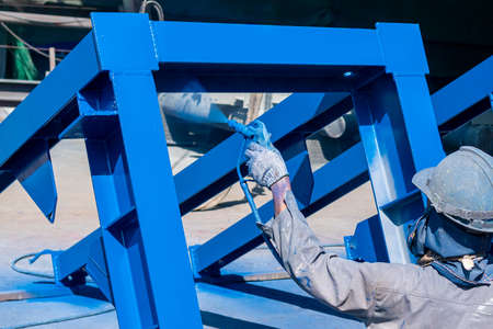 After complete fabrication at an industrial factory, the painter uses a spray gun to paint a steel structure.の写真素材