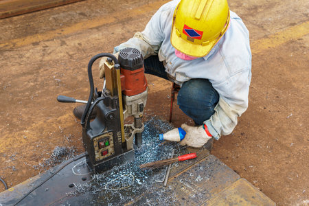 Worker drilling a hole on a gusset plate with portable magnetic drillsの写真素材