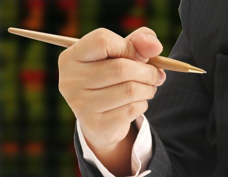 Closeup business man hold a pen and stock exchange board backgroundの写真素材