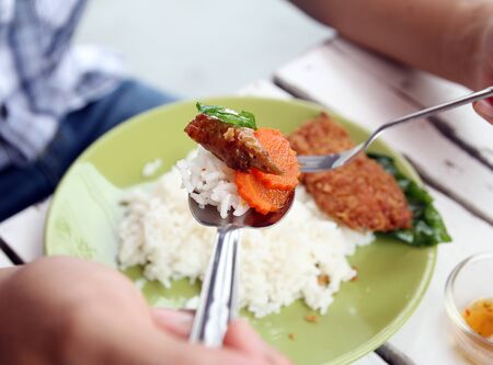 Closeup image of man eating Thai food, roast duck with basil and carrotの写真素材