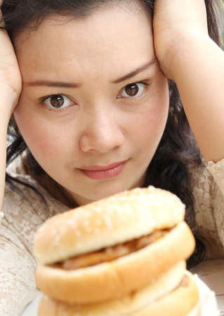 Image of woman thinking between diet or eating hamburger and sandwichの写真素材