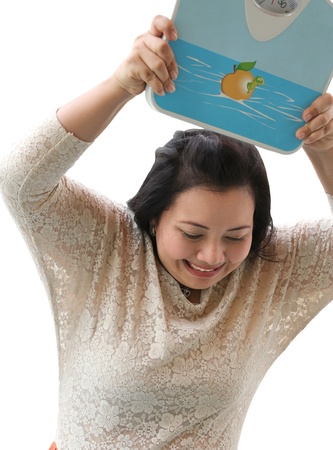 Image of angry woman holding weight scale over her headの写真素材