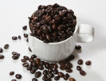 Closeup image of coffee beans and coffe cup on white tableの写真素材