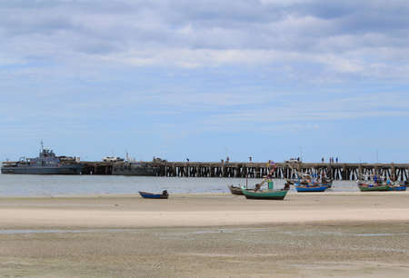 Image of warships standby at harbor and fishing boats on the beach waiting high tide in eveningの写真素材