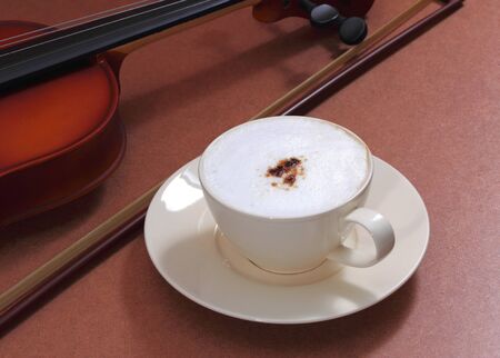 close up image of hot coffee and white cup with violin in coffee shopの写真素材