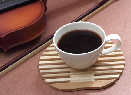 close up image of hot coffee and white cup with violin in coffee shopの写真素材
