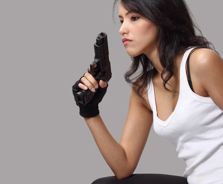 asian woman wearing white vest and holding a gun on her hand の写真素材