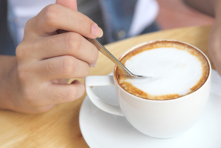 Closeup image of women and her hot coffee in white cup on tableの写真素材