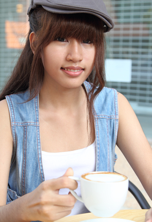 Image of young asian woman holding hot coffee on her hand at coffee shopの写真素材