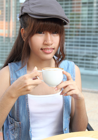Image of young asian woman holding hot coffee on her hand at coffee shopの写真素材