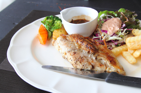 Closeup image of pork steak with french fried and salad on tableの写真素材