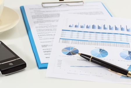 image of graphics and finance report for business with pen mobile phone and coffeeの写真素材