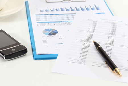 image of graphics and finance report for business with pen mobile phone and coffeeの写真素材