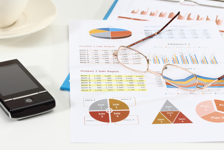 image of graphics and finance report for business with glasses and mobile phoneの写真素材
