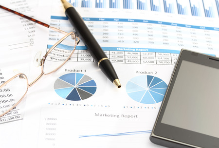image of graphics and finance report for business with pen glasses and mobile phoneの写真素材